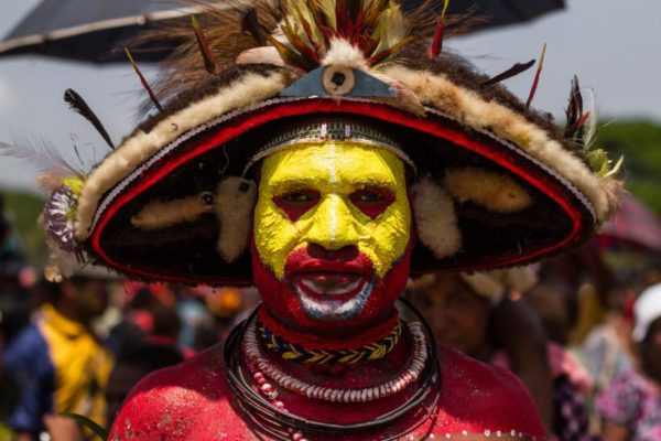 Port Moresby, 2013. The Huli are the largest ethnic group in the Highlands and are known for their distinctive red and yellow face paints. They also wear decorative woven wigs, specially made by a unique clan known as the Huli Wigmen, who weave the wigs out of matted hair anointed with ritual water.