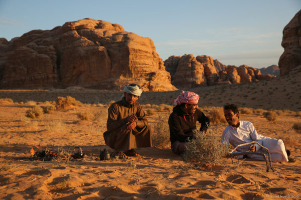 Three Bedouin guides prepare hot tea in the setting sun.