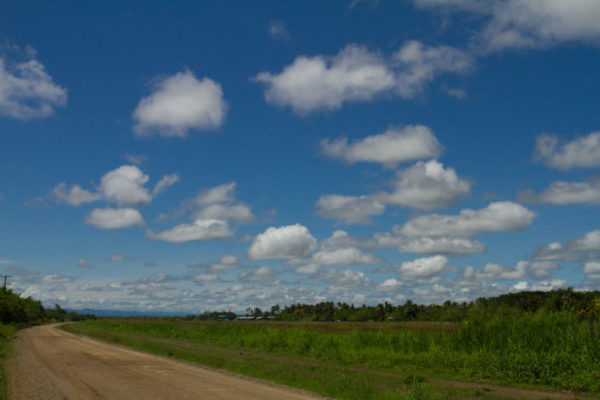 The dirt road winds its way past Malalaua on a picture perfect day, the clouds seemingly outlined on the canvas of the sky.