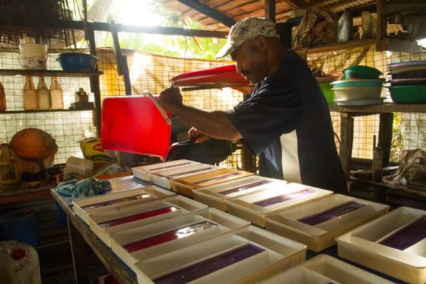 A man pours homemade soap into containers, one of the many entrepreneurial activities in the village.