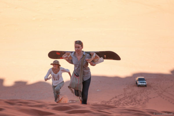 Dune surfing down the red sand dune of Wadi Rum