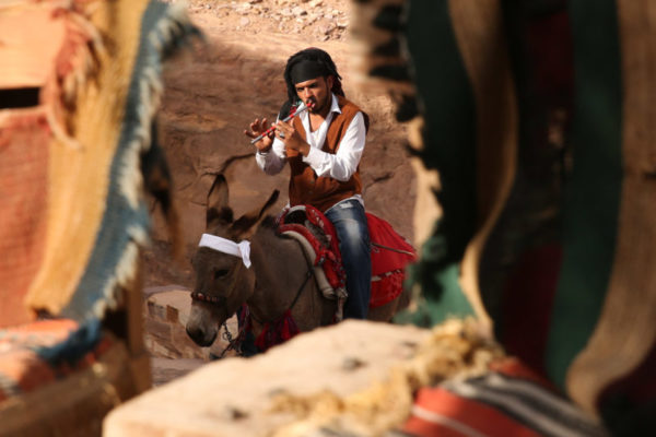 A young man plays the flute while riding a donkey to the Monastery.