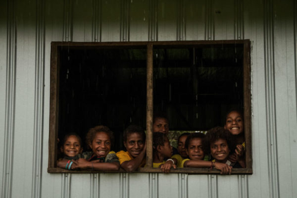 Moro, Southern Highlands, 2013. During an early morning downpour, students huddle around an open window to watch the rain.