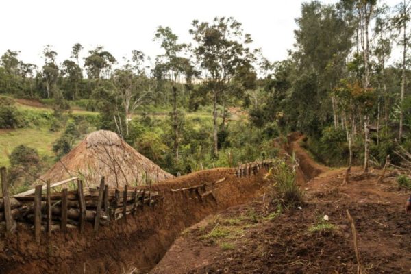 Hides, Hela Province, 2012. The Huli tribe is known for digging a long and steep ditch around the perimeter of villages or homesteads as a means of protection. The ditches take days to construct and can only be crossed by using a thin bridge